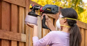 Woman-using-wagner-paint-sprayer-on-fence